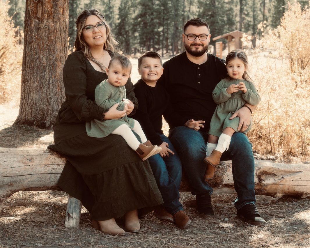 Steven Arnold with his wife and three children, outdoors under a pine tree
